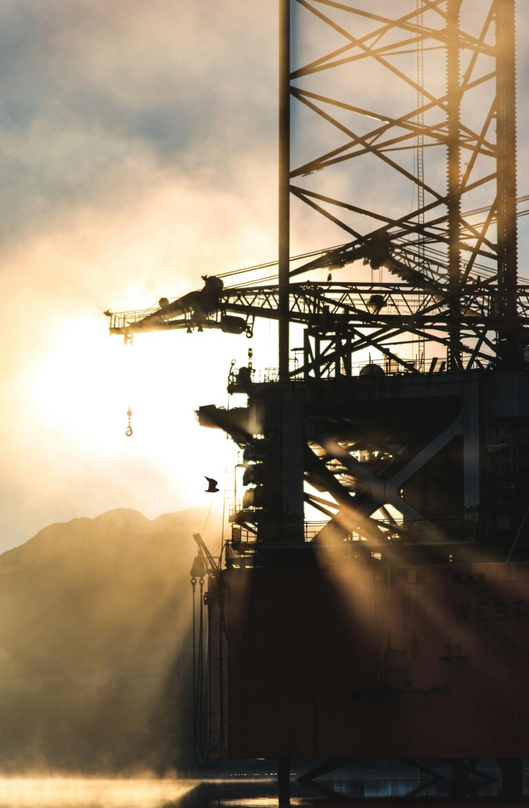 Dramatic silhouette of industrial machinery against a foggy morning sunrise, capturing the essence of heavy industry.